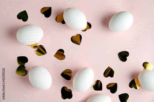 top view on easter eggs on pink background .tinsel of golden hearts on a pink background.preparation for Easter.  selective focus 