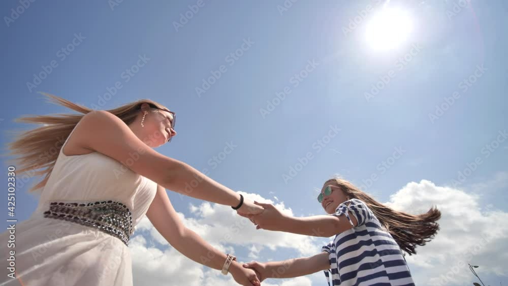 Happy girlfriends are spinning by the arms on a warm summer day.