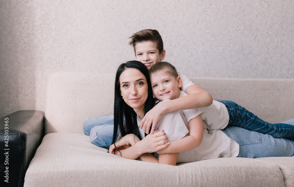 two young sons lie on their mother's back and hug her. two young sons lie on their mother's back and hug her.