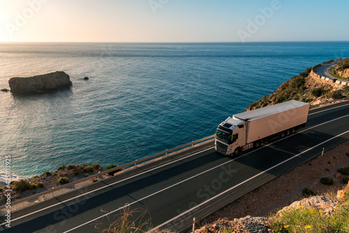 Fototapeta Naklejka Na Ścianę i Meble -  Truck with refrigerated semi-trailer driving on a road by the sea.