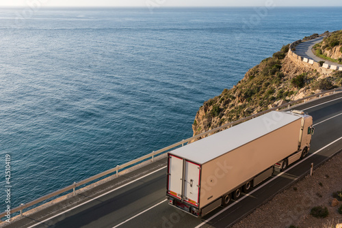 Truck with refrigerated semi-trailer driving on a road by the sea. photo