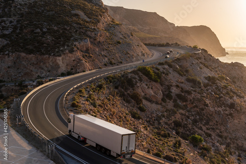 Truck with refrigerated semi-trailer driving on a mountain road by the sea. photo