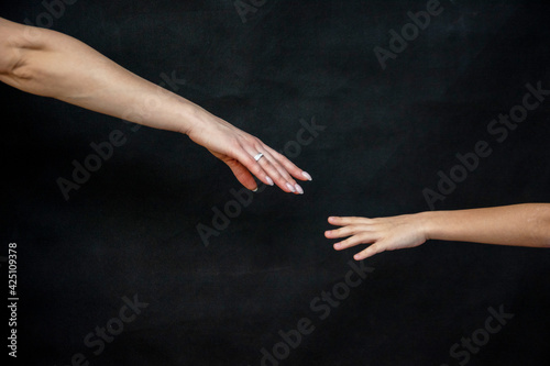 child holding his mother's hand in close-up on a black background.
