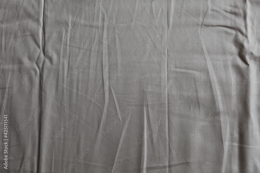 A nice crumpled fabric with creases of beige sand color can be a tablecloth or a sheet used as a background A nice crumpled fabric with creases of beige sand color can be a tablecloth or a sheet used as a background