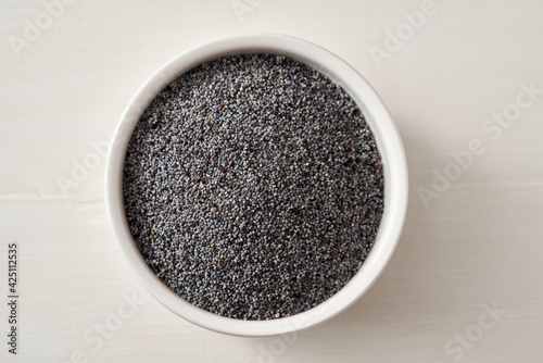 Poppy seeds in a bowl on a white background, top view