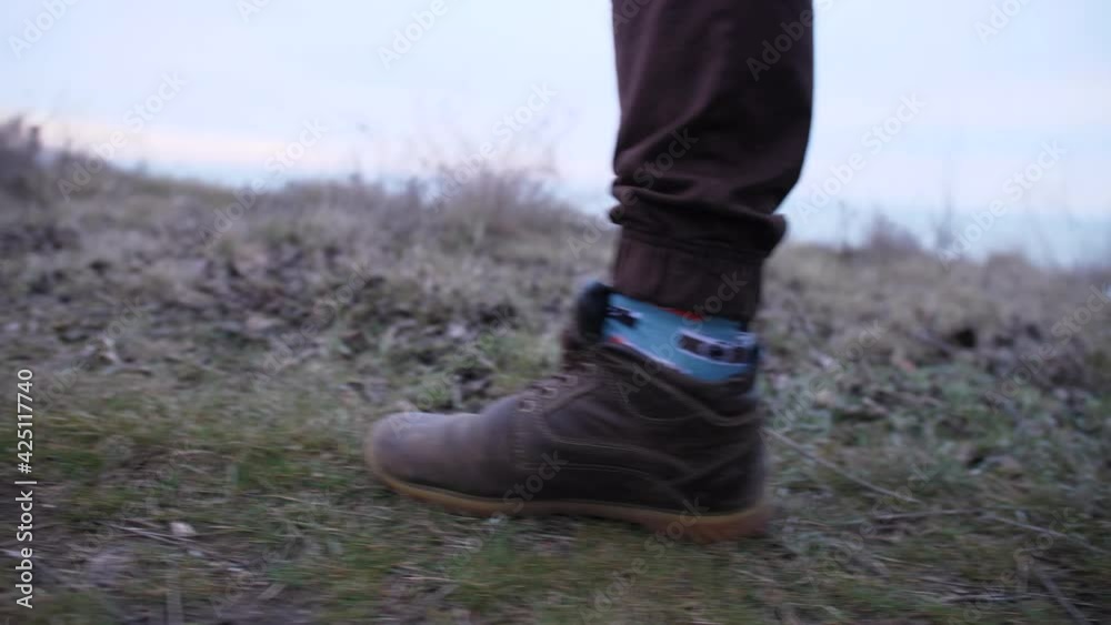Feet in boots and colored socks shot of hiker that walks on a hills in late autumn weather