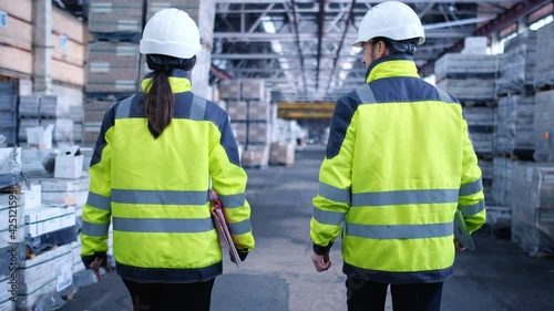 Follow footage of employees male and famale warehouse worker engineer in hard hat working. walking through logistics center warehouse factory construction site logistics architect businessman man