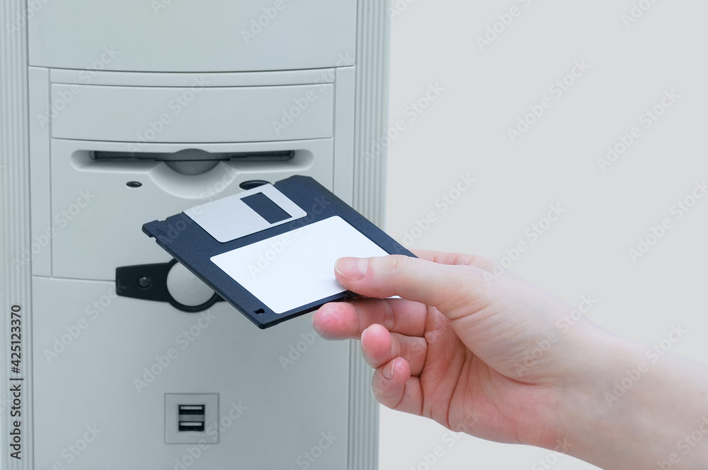 A hand inserts a floppy disk into personal computer. Retro technology.  Stock Photo | Adobe Stock