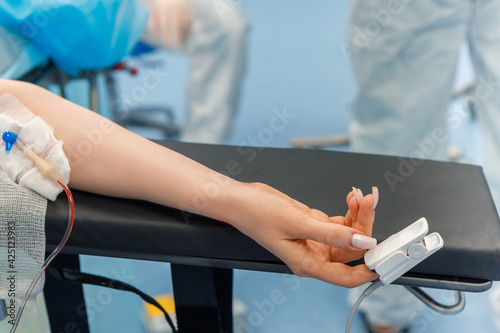 The patient's hand is under the IV with a pulse oximeter on the finger.