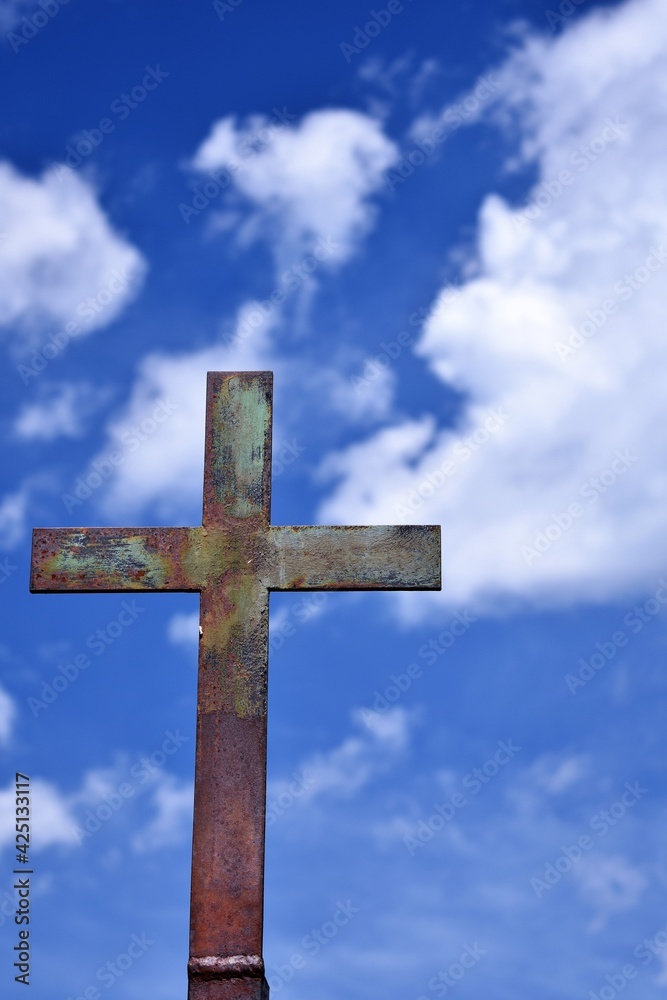Cemetery cross against blue sky with clouds