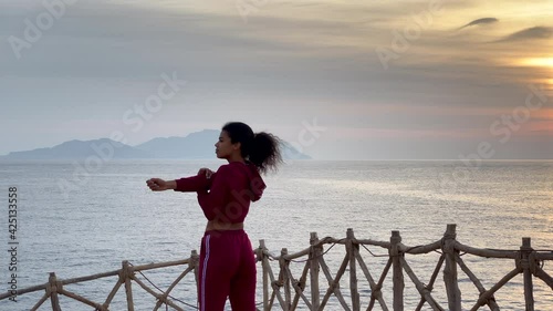 Inspired. Rear view of young woman doing exercises, stretching her body at sunrise outdoors. Slow motion. Body positive, healthy lifestyle, nature concept