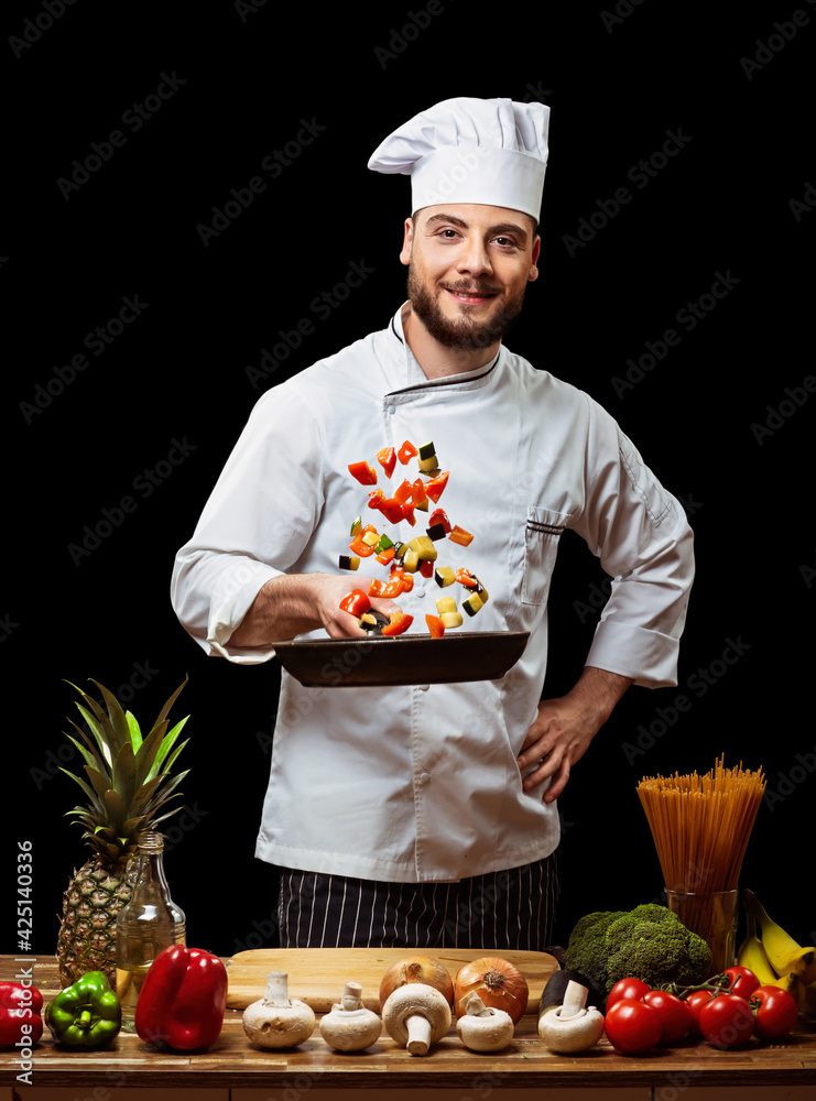Handsome Italian chef tosses chopped vegetables in a frying pan