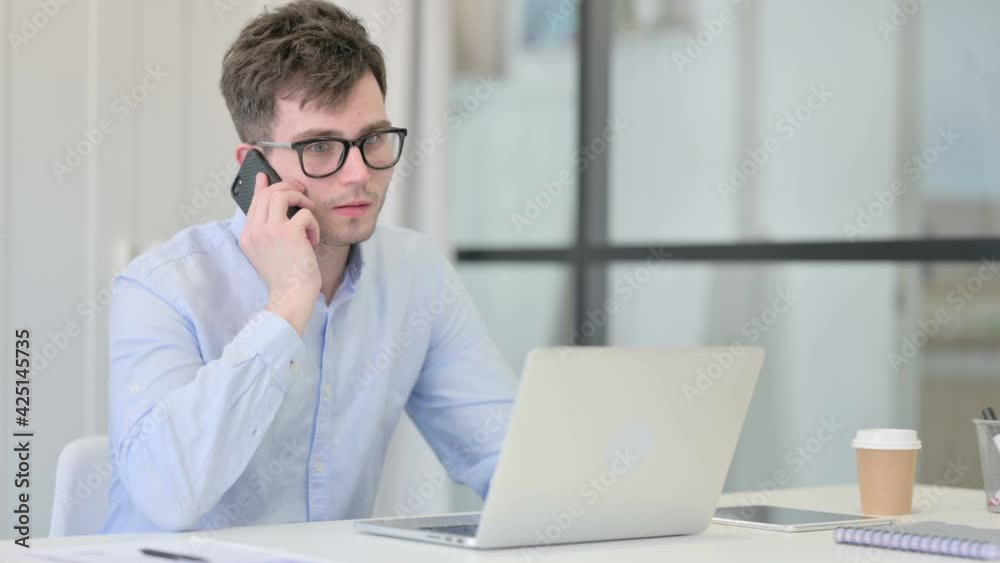 Young Man with Laptop Talking on Phone Young Man with Laptop Talking on Phone