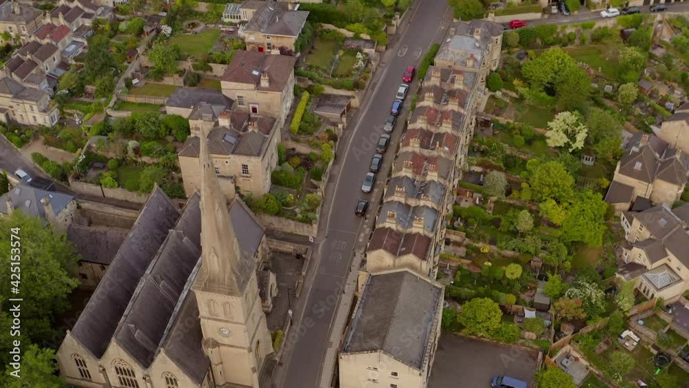 Aerial tilting up from church to reveal residential houses surrounded by lush green countryside in the English town of Bath United Kingdom Aerial tilting up from church to reveal residential houses surrounded by lush green countryside in the English town of Bath United Kingdom