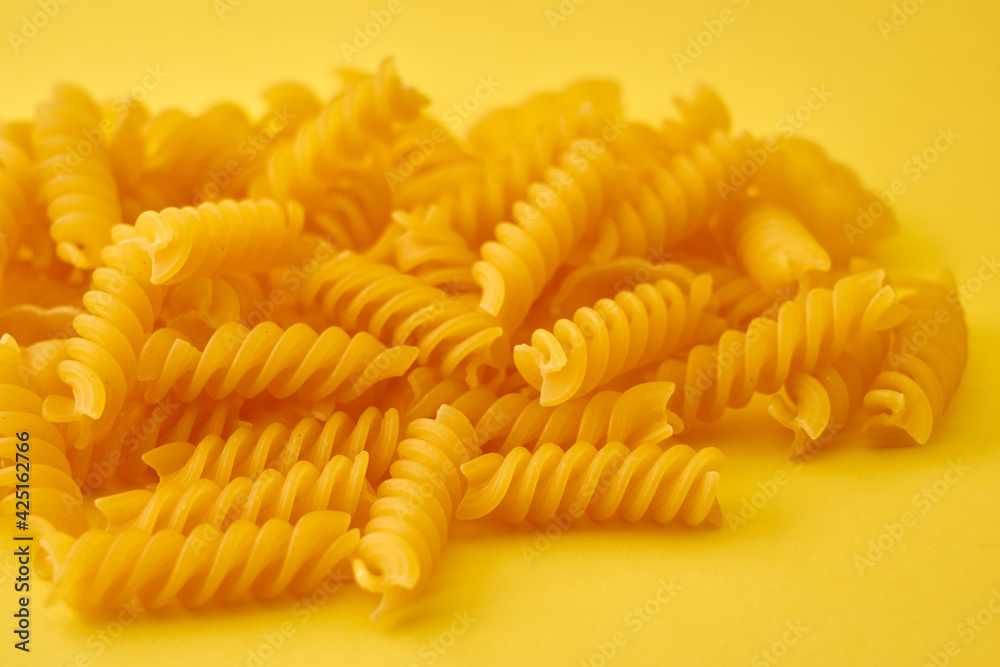 Pasta in the form of spirals on a bright yellow background. Pasta in the form of spirals on a bright yellow background.