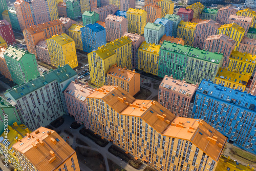 Multicolored colorful apartment buildings (block of flats) in a residential area (dormitory district or bedroom community) of a large city. Aerial view on a sunny day.