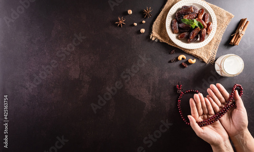 Ramadan Kareem background concept, Hands holding rosary bead with dates fruit and milk on dark stone background. photo