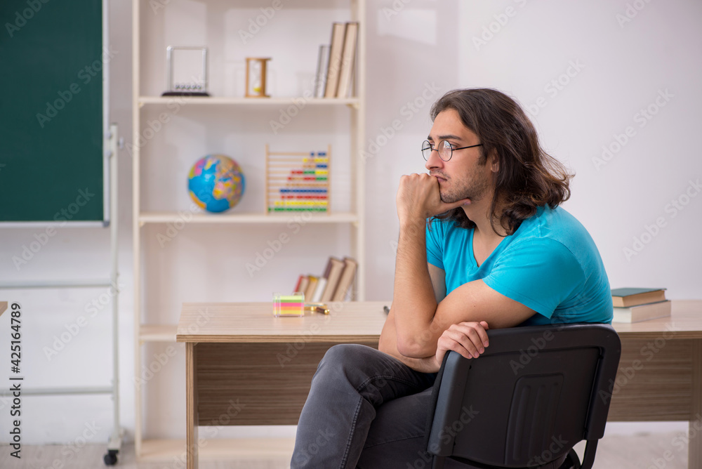 Young male student in front of green board