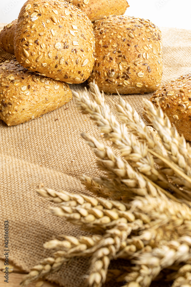 Home baked bread. Rye bakery with crusty loaves and crumbs. Fresh rustic traditional bread with wheat grain ear or spike plant on natural cotton background. Design element for bakery product label. Home baked bread. Rye bakery with crusty loaves and crumbs. Fresh rustic traditional bread with wheat grain ear or spike plant on natural cotton background. Design element for bakery product label.