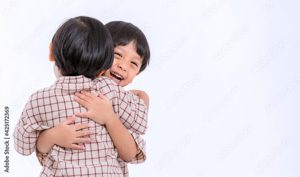 Twin boys hugging on white background. Portrait of little son hugging brother or friend. I missing you. Full length happy boy embracing glad brother or friend while standing indoor. Positive meeting Twin boys hugging on white background. Portrait of little son hugging brother or friend. I missing you. Full length happy boy embracing glad brother or friend while standing indoor. Positive meeting