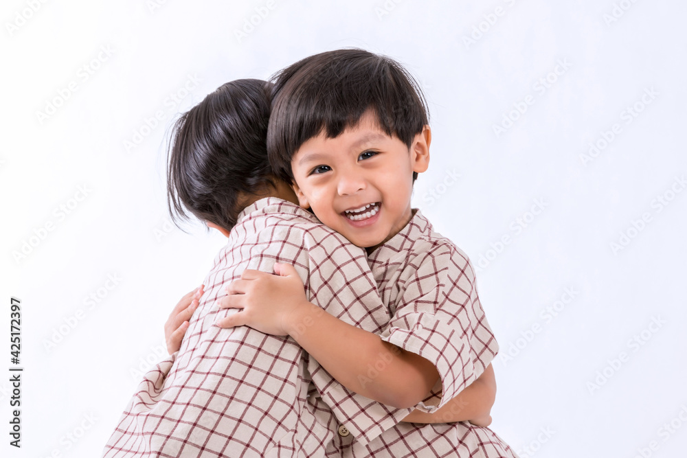 Twin boys hugging on white background. Portrait of little son hugging brother or friend. I missing you. Full length happy boy embracing glad brother or friend while standing indoor. Positive meeting Twin boys hugging on white background. Portrait of little son hugging brother or friend. I missing you. Full length happy boy embracing glad brother or friend while standing indoor. Positive meeting