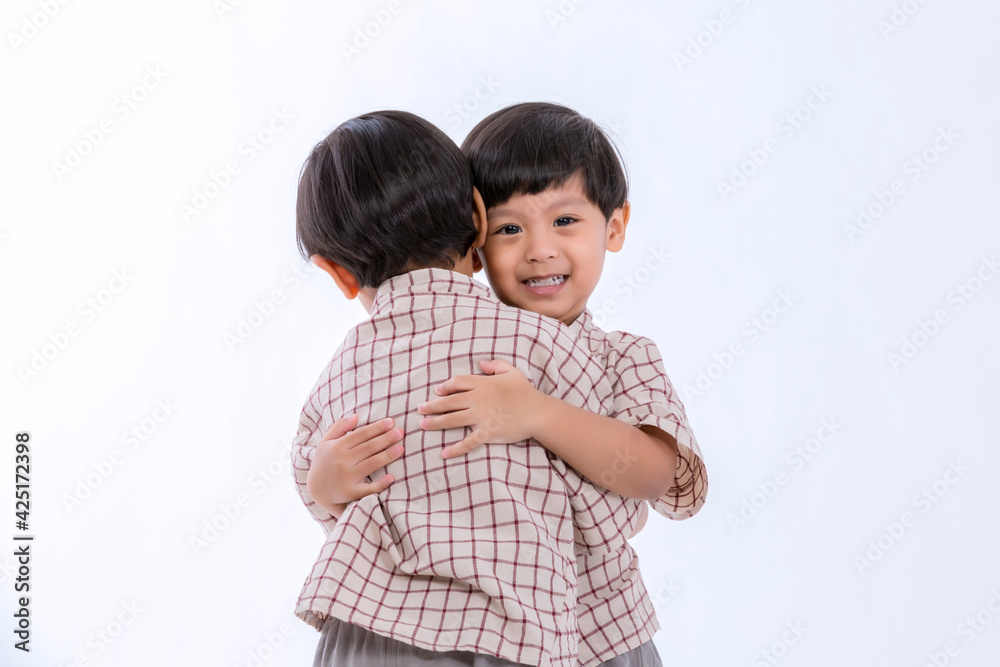 Twin boys hugging on white background. Portrait of little son hugging brother or friend. I missing you. Full length happy boy embracing glad brother or friend while standing indoor. Positive meeting Twin boys hugging on white background. Portrait of little son hugging brother or friend. I missing you. Full length happy boy embracing glad brother or friend while standing indoor. Positive meeting