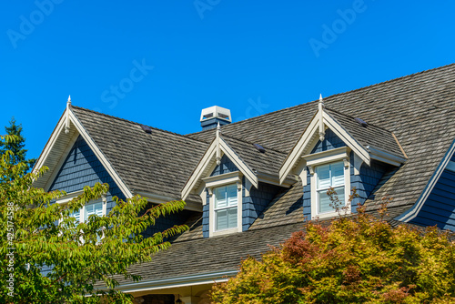 A perfect neighborhood. Houses in suburb at Summer in the north America. Top of a luxury house with nice window over blue sky.