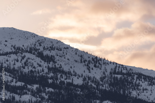 Stunning winter view in northern Canada during March, spring time with pink sunset views, wilderness mountains for tourism, tourist, travel background. 