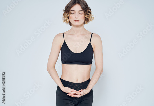 Woman in sportswear is engaged in fitness on a light background cropped view