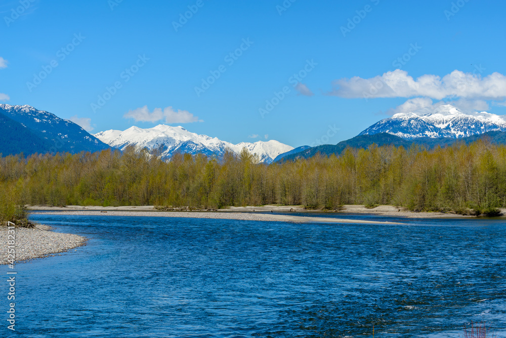 Majestic mountain river in winter over snow mountains and blue sky in Vancouver, Canada.