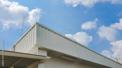 metal roof panel with blue sky and white clouds in the background.