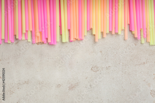 Colorful plastic drinking straws on grey stone table  flat lay. Space for text