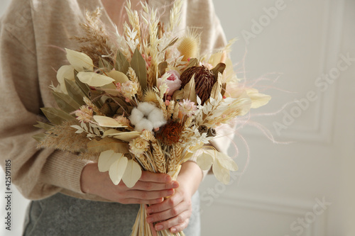 Fototapeta Naklejka Na Ścianę i Meble -  Woman holding beautiful dried flower bouquet at home, closeup