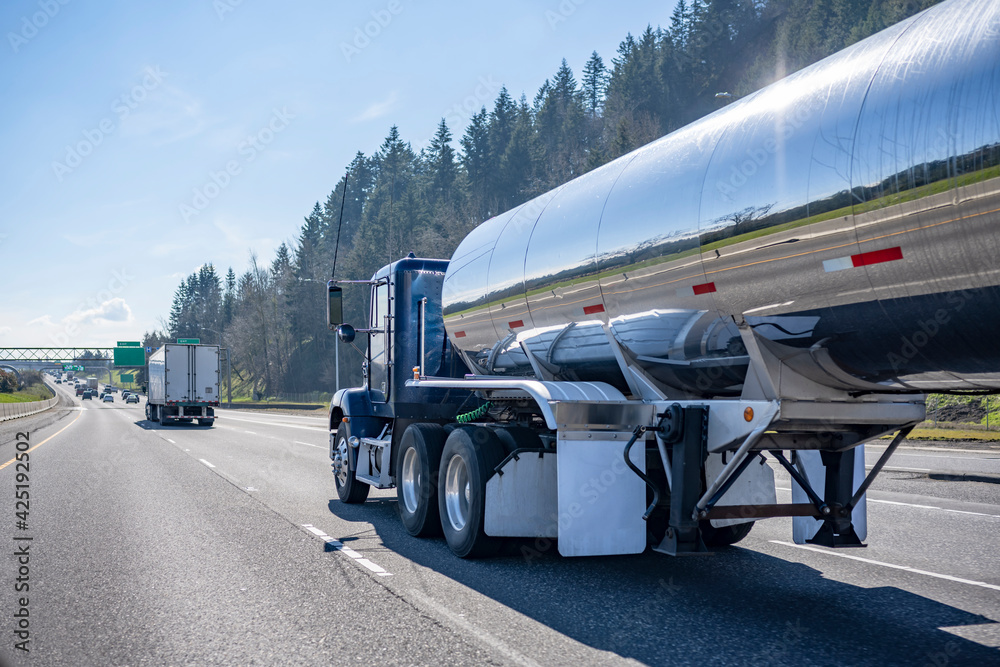 Φωτογραφία Blue big rig semi truck with shiny tank semi trailer driving on the wide highway