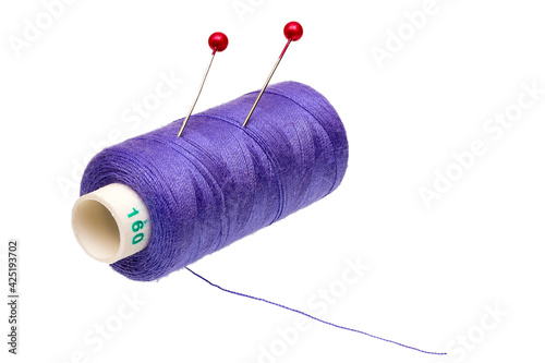 Spool of thread with stuck pins isolated on white background photo