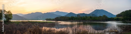 panorama beautiful landscape hills and meadow with orange sky reflection in water. mountain lake in the sunset.