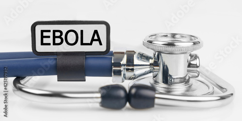 On the white surface lies a stethoscope with a plate with the inscription - EBOLA