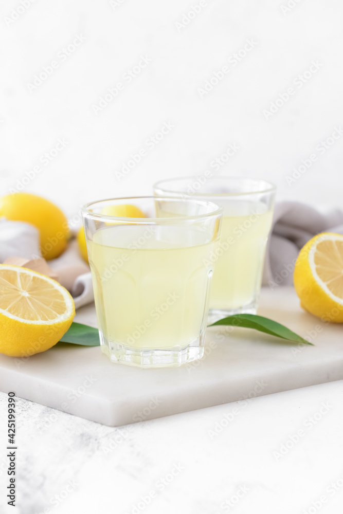 Fresh lemons and glasses of juice on light background Fresh lemons and glasses of juice on light background