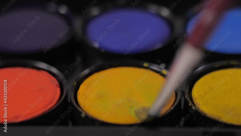 artist painter mixing water and yellow watercolor with brush artist painter mixing water and yellow watercolor with brush