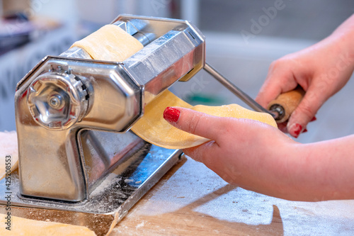 Pasta maker. dough. Woman's hand. The concept of making dough and pasta at home. Preparing fresh  rolling dough with a pasta Machine. photo