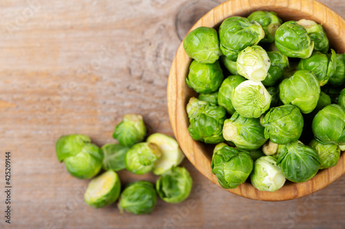 Fresh raw brussels sprouts in a bowl on a wooden table.