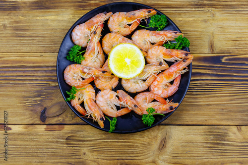 Red boiled prawns with lemon and parsley on wooden table. Top view