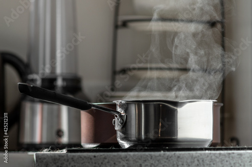 Stainless steel pot on an electric stove in the kitchen. Selective focus  blurred background.