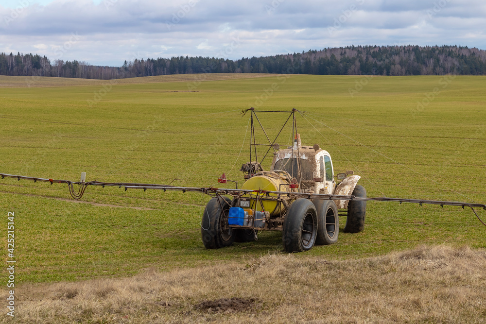 Obraz premium Street lighting. special machine on wheels for gentle spraying of crops in the field. Filled with fertilizer for plants.