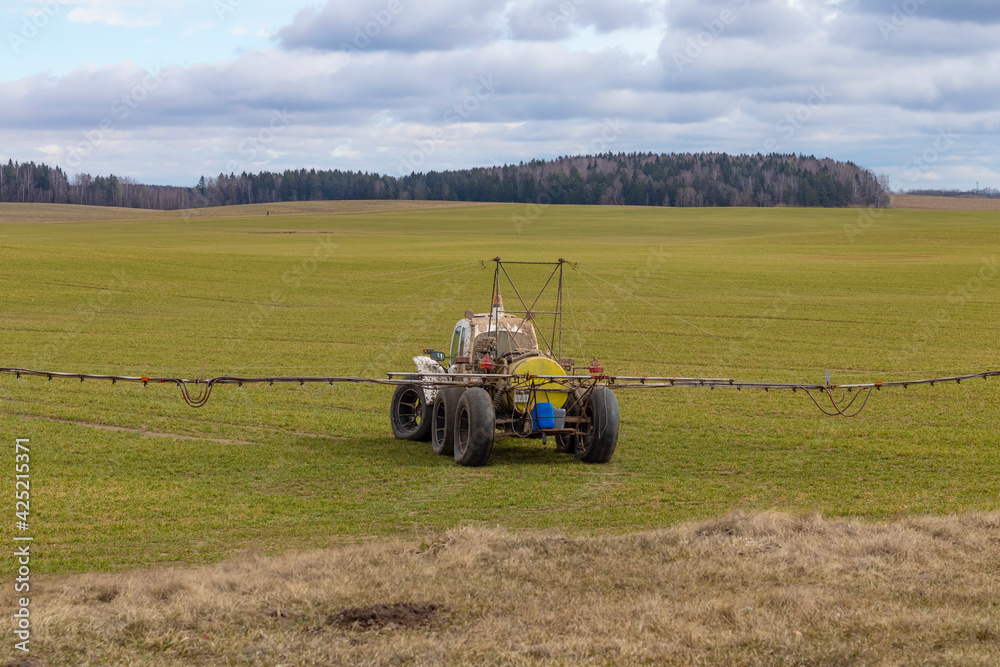 Fototapeta premium Street lighting. special machine on wheels for gentle spraying of crops in the field. Filled with fertilizer for plants.