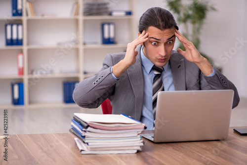 Young male employee unhappy with excessive work in the office