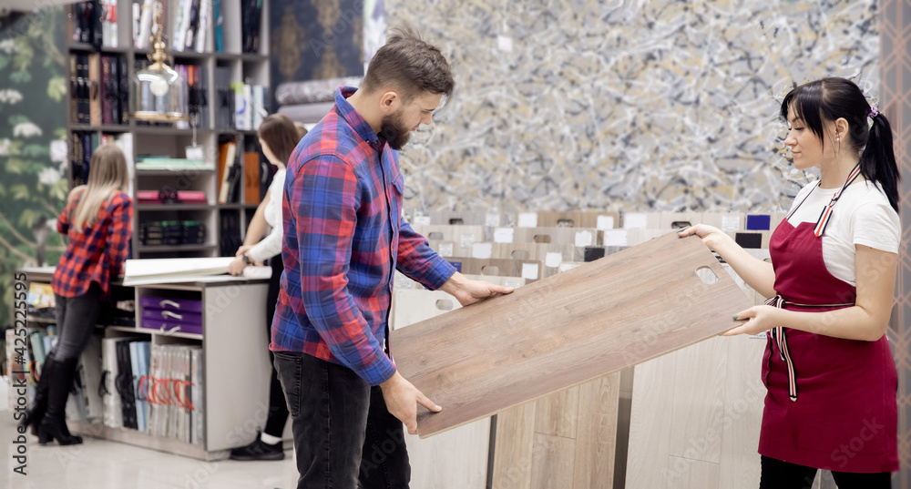 Laminate on market, male worker chooses parquet flooring in house, consultant talks about advantages of material