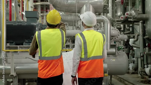 Engineer and Foreman are discussing the plant layout on the blueprint in the factory boiler room
