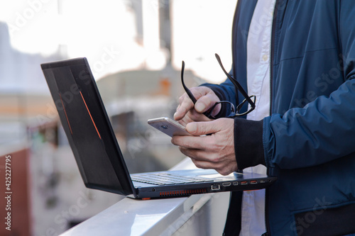 man using his laptop and consulting the mobile phone