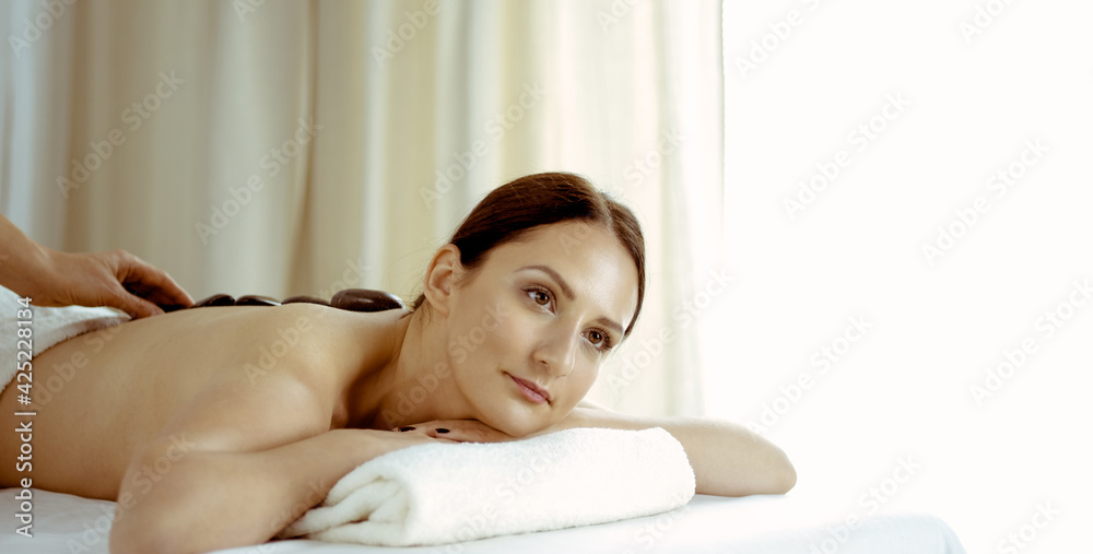 Pretty brunette woman enjoying treatment with hot stones in spa salon. Beauty concept Pretty brunette woman enjoying treatment with hot stones in spa salon. Beauty concept